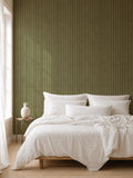 Olive and dusty pink striped wallpaper in a cozy bedroom with white bedding.