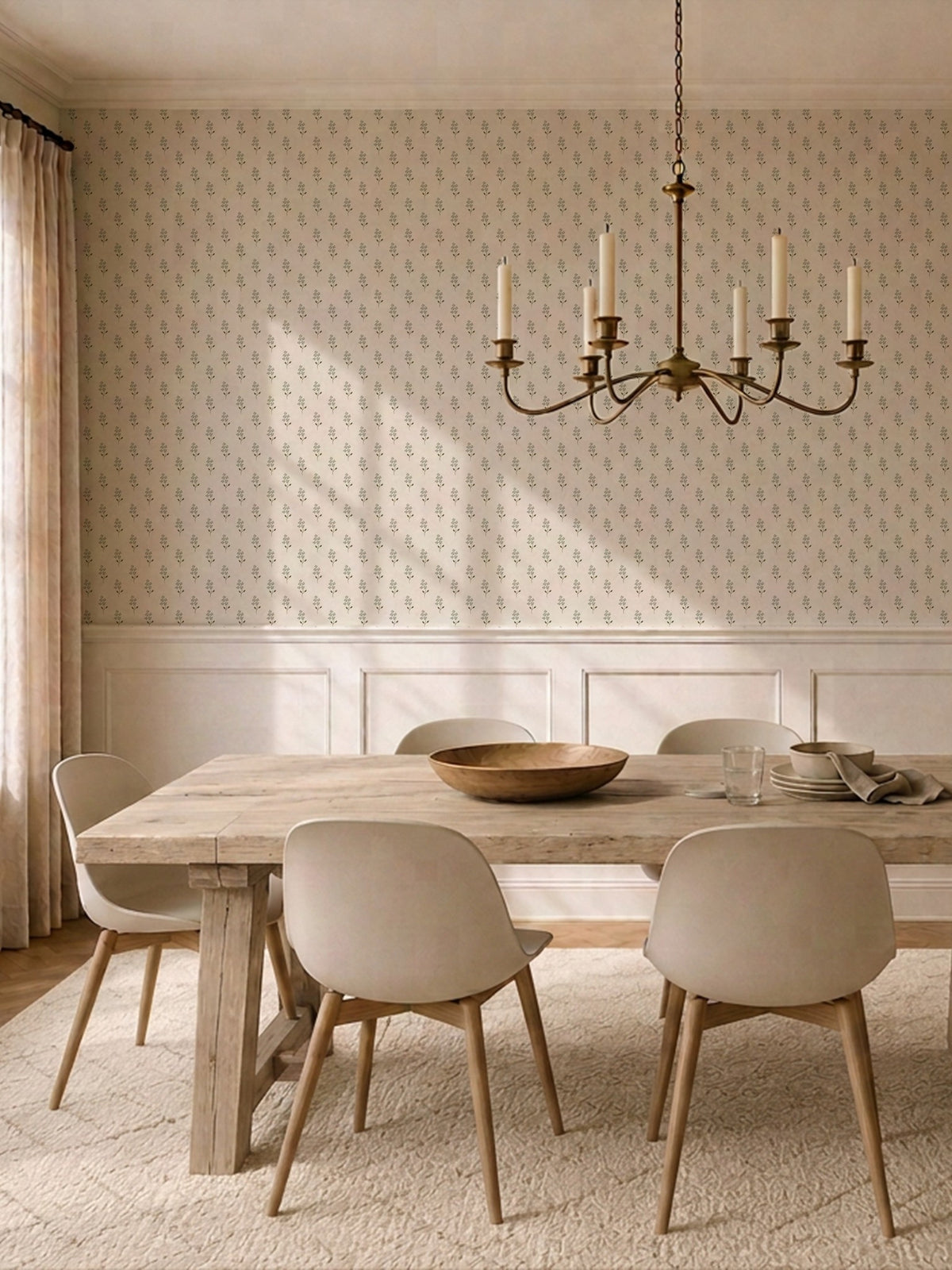 Sage green floral wallpaper in rustic dining room with wooden table and chandelier.