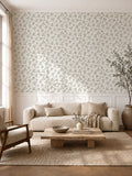 Sage green leaf sprig wallpaper in a cozy living room with natural wood furnishings.