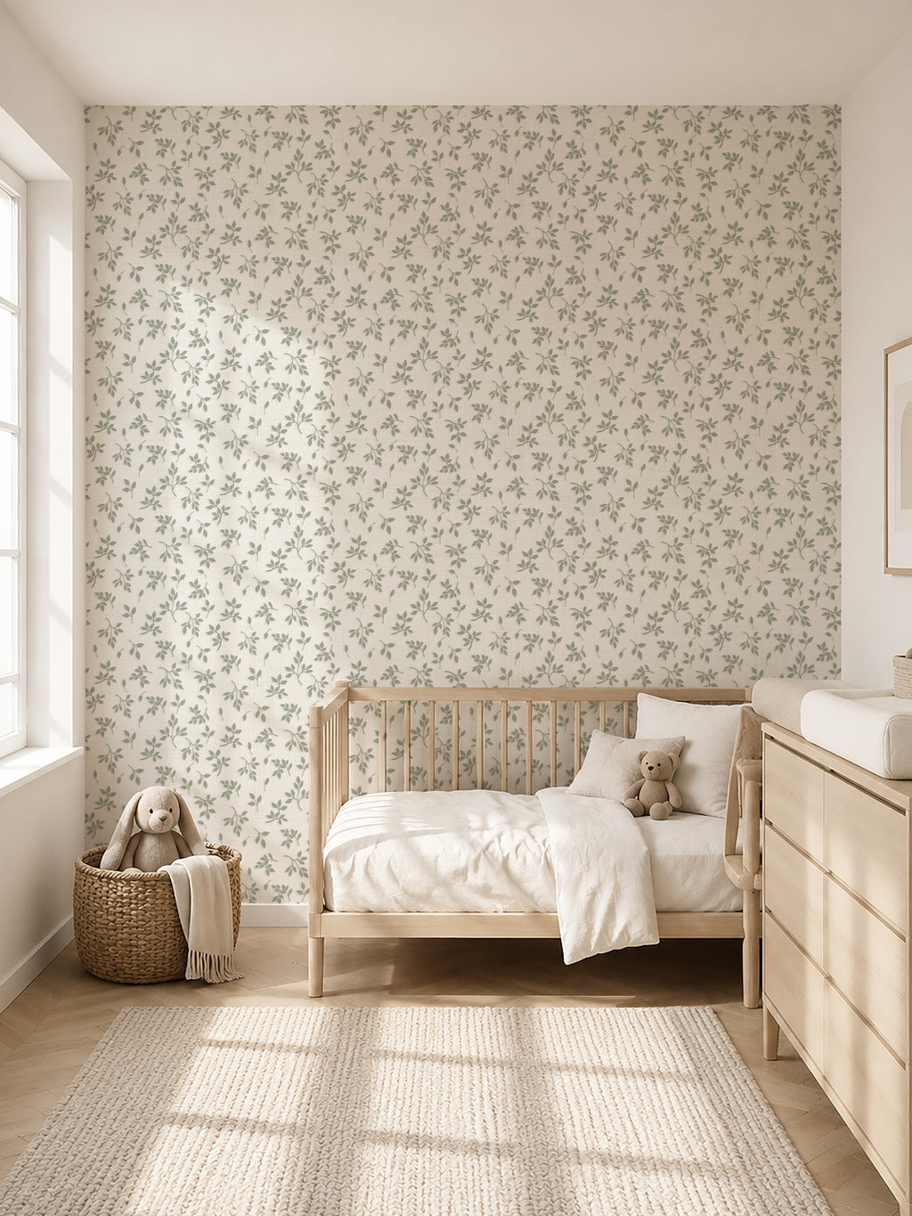 Sage green leaf sprig wallpaper in a bright nursery with wooden crib and dresser.